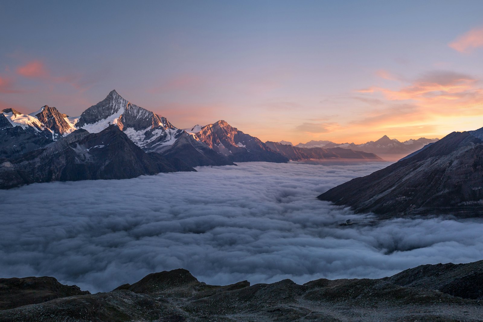 Alpine peaks above a sea of cloud at sunset, the kind of footage playing while you row